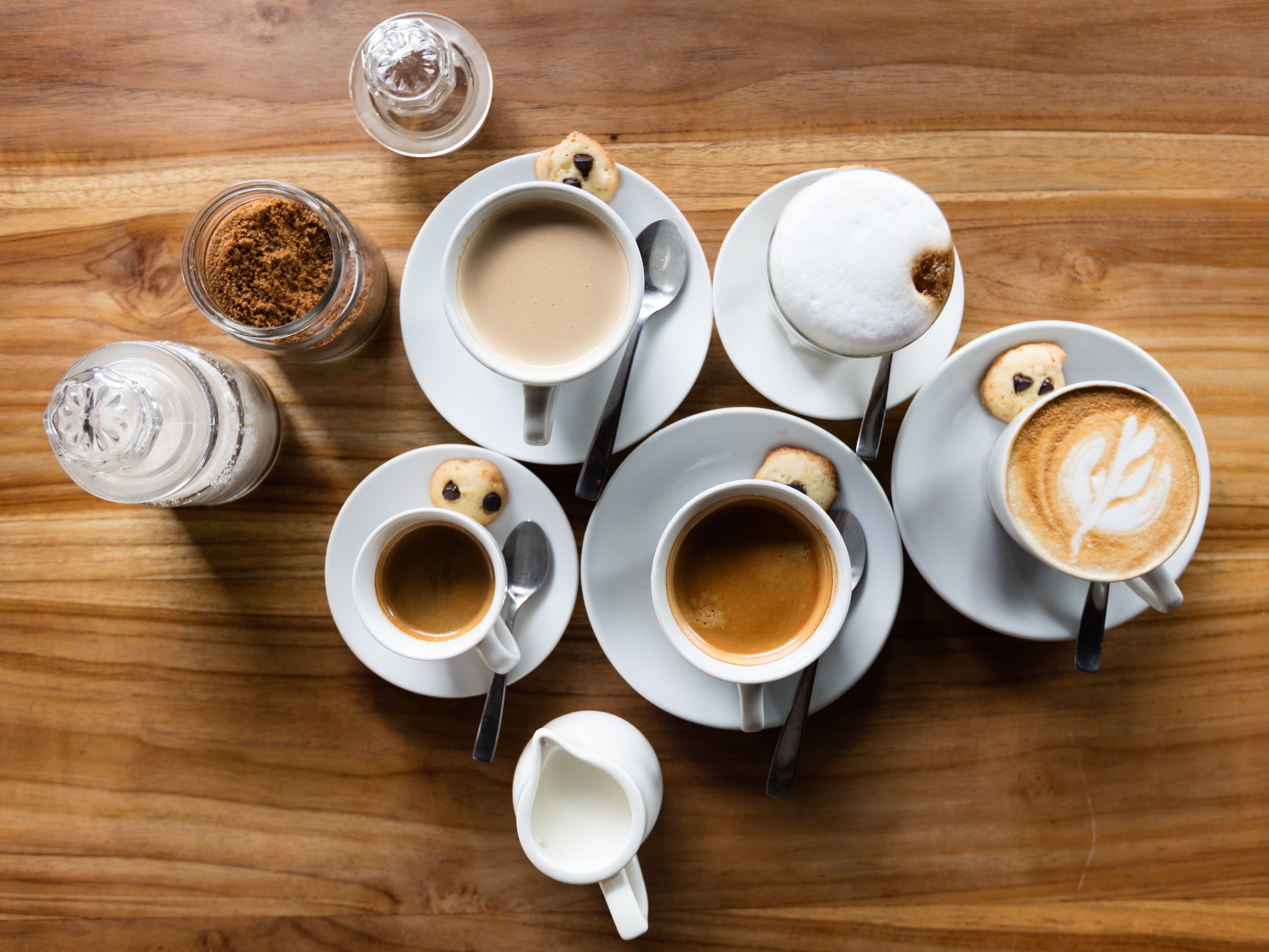 An overhead shot of five white cups with various kinds of coffee