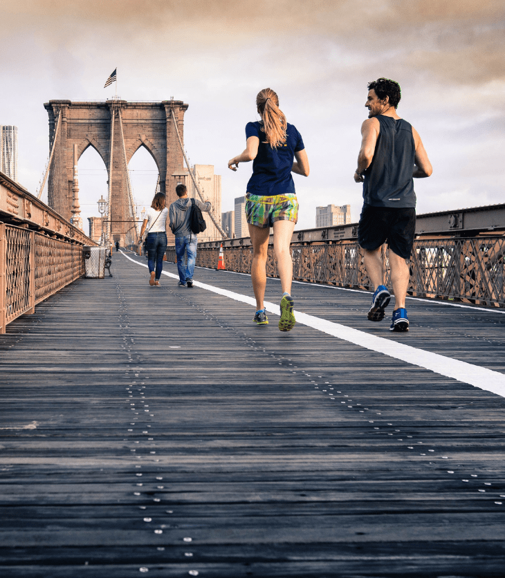 Man and woman running over the Brooklyn Bridge