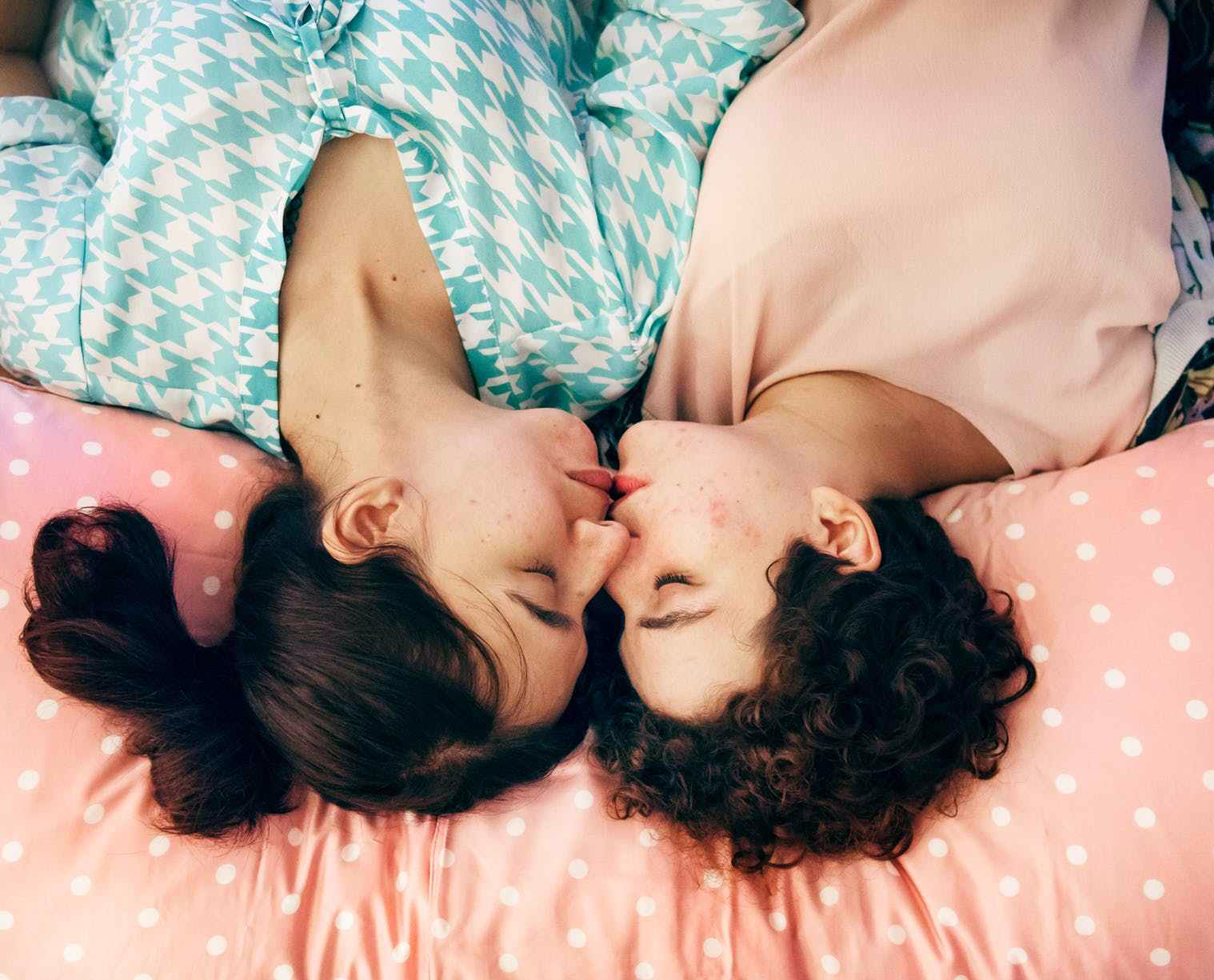 two woman kissing on bed