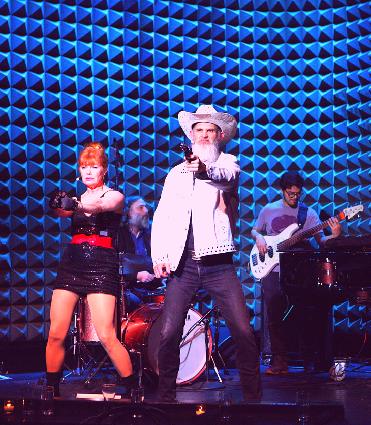 man on stage with woman and guitarist