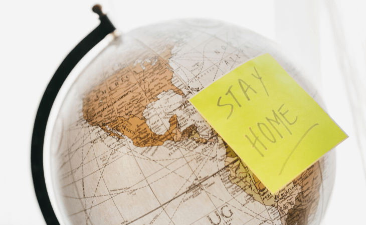 world globe with post it note saying stay home