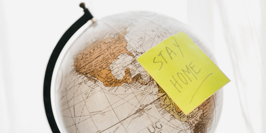world globe with post it note saying stay home