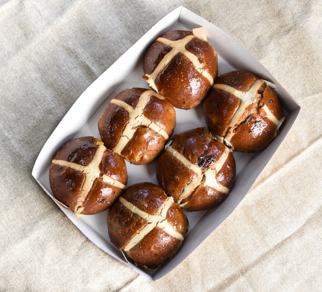 box of six hot cross buns or easter buns on a light brown table cloth